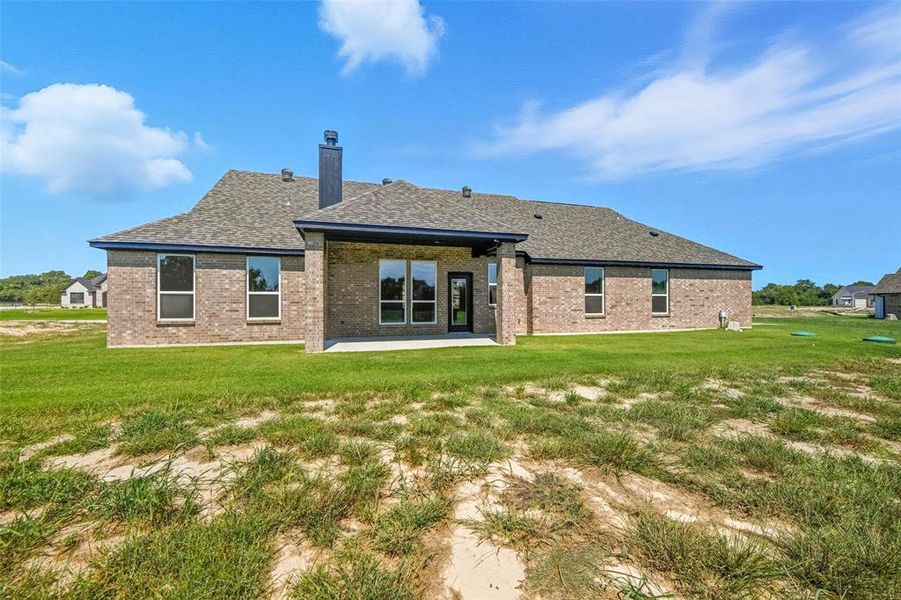Rear view of house featuring brick siding, a yard, a patio area, and roof with shingles Rear view of house featuring brick siding, a yard, a patio area, and roof with shingles