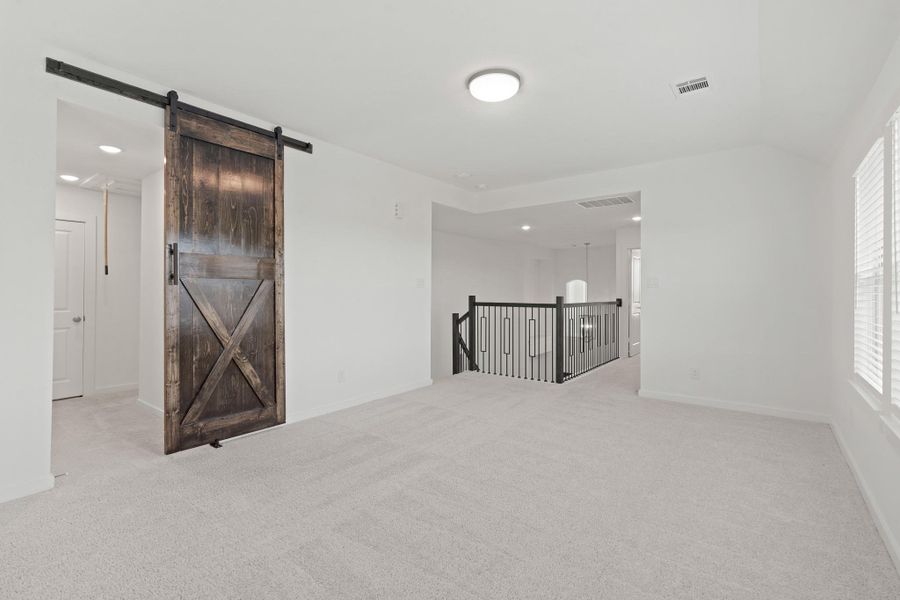 Endless possibilities await in this spacious bonus room! With expansive windows overlooking the backyard and custom sliding barn door, this versatile space is ready to transform.