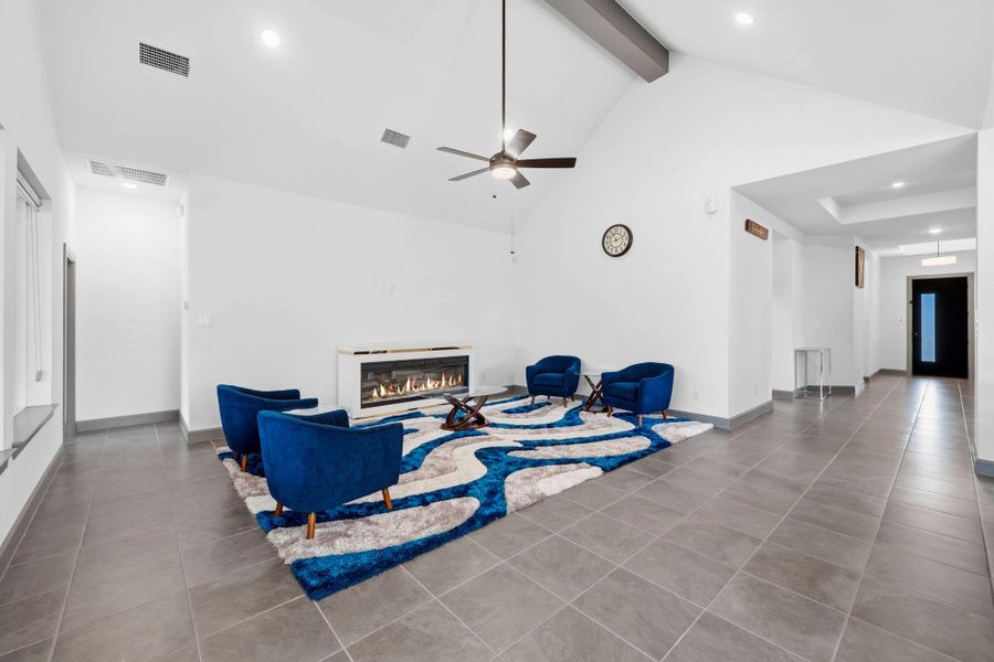 Expansive open-concept living space with soaring ceilings, modern fireplace, and abundant natural light—perfect for both entertaining and relaxed everyday living.