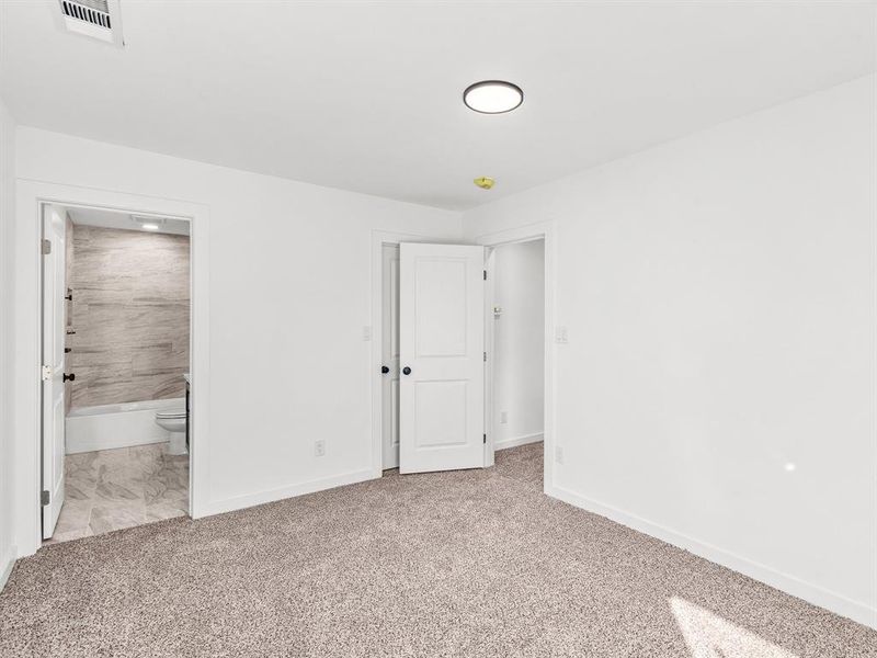 Unfurnished bedroom featuring light carpet and ensuite bathroom