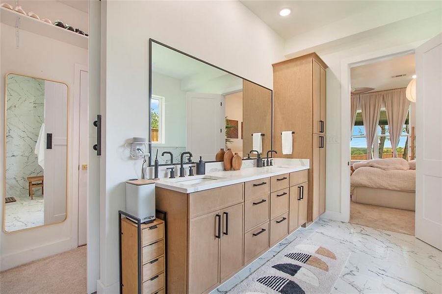 Ensuite bathroom with double vanity, healthy amount of natural light, light marble finish flooring, and recessed lighting Ensuite bathroom with double vanity, healthy amount of natural light, light marble finish flooring, and recessed lighting