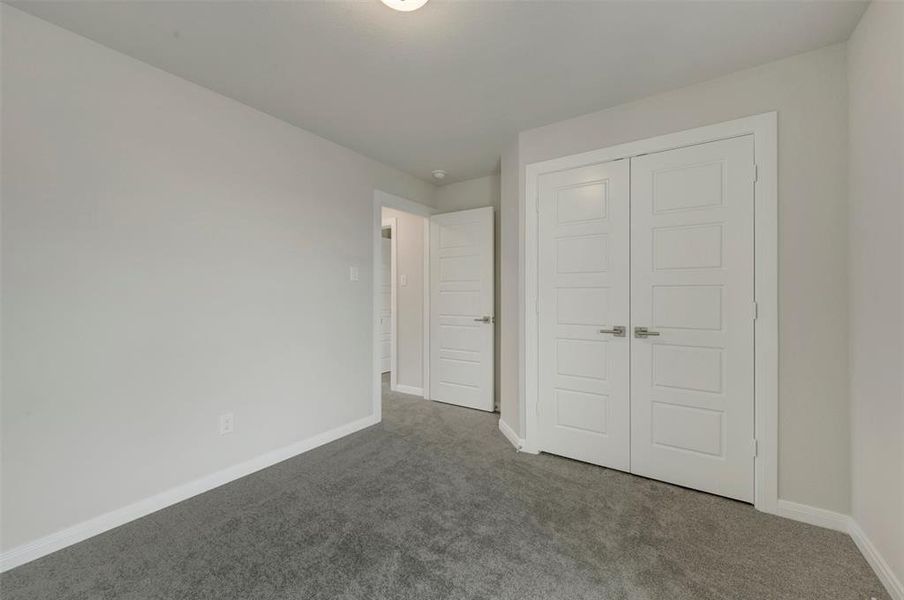 Interior room featuring plush gray carpeting, light-toned wall paint, and white baseboards