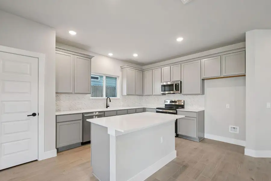 Kitchen with gray cabinetry, light wood-type flooring, stainless steel appliances, and recessed lighting