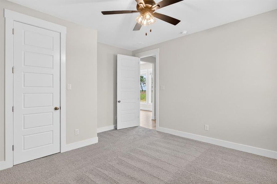 Spacious room featuring light gray carpeting, neutral wall finishes, and a contemporary ceiling fan with integrated lighting Spacious room featuring light gray carpeting, neutral wall finishes, and a contemporary ceiling fan with integrated lighting