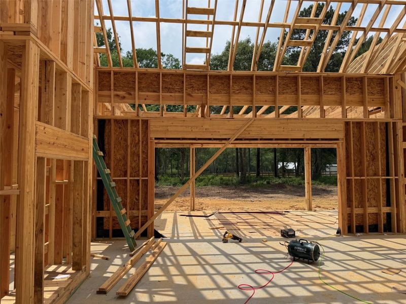 New construction framing featuring a concrete slab foundation, extensive wood framing, and open ceiling joists