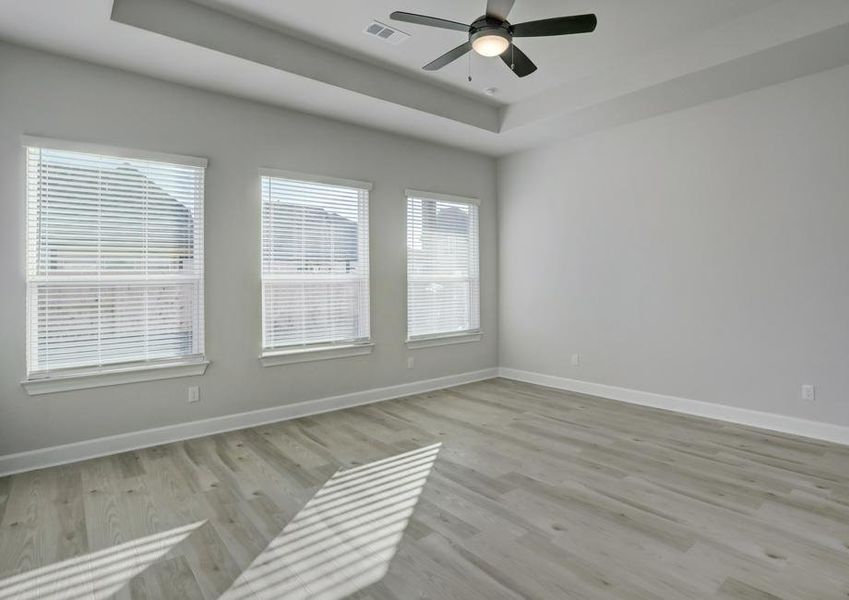 Master bedroom with three large windows that allow natural light in.