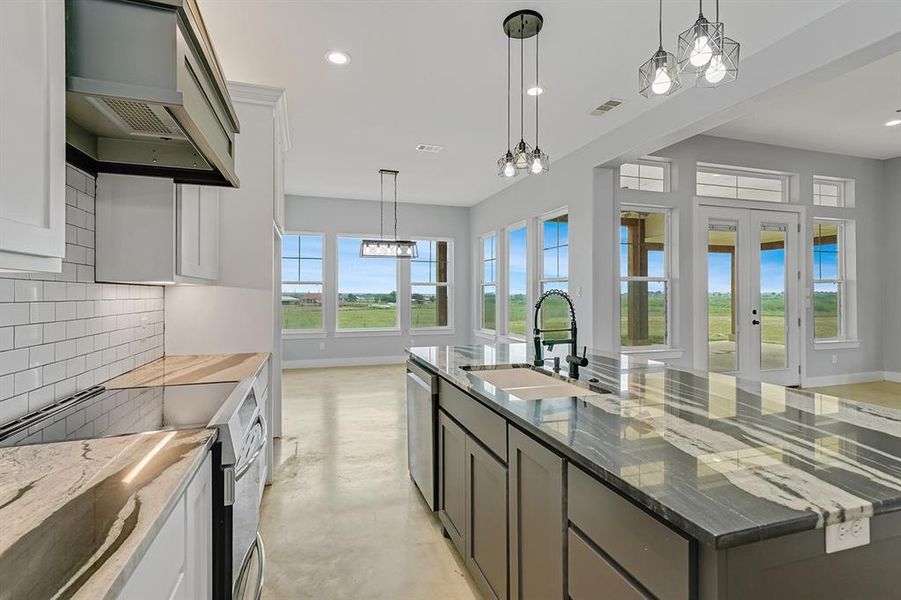 Kitchen with appliances with stainless steel finishes, a sink, tasteful backsplash, premium range hood, and baseboards