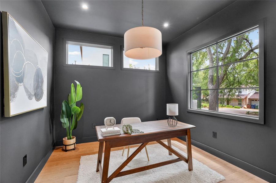 A well-lit study with hardwood flooring and contemporary windows invites productivity.