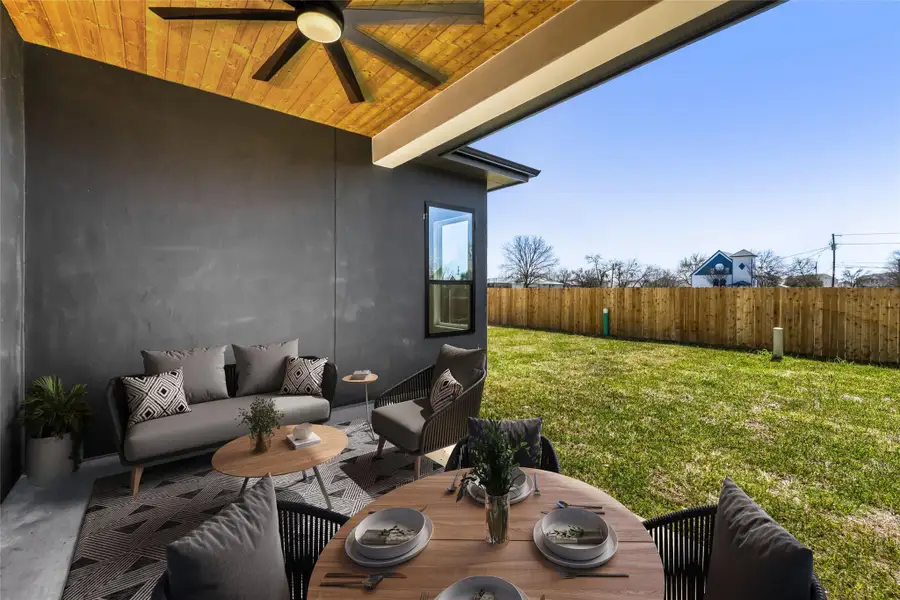 The entertainer's covered back porch is ready for your ideal outdoor living set up under sleek wood wrapped ceiling with an oversized designer fan. (virtually staged photo)