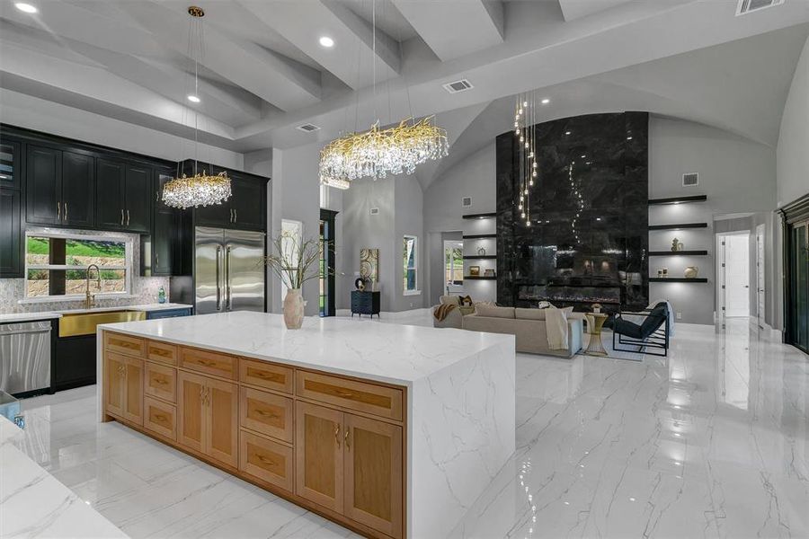 Kitchen featuring a center island, hanging light fixtures, light stone counters, and appliances with stainless steel finishes