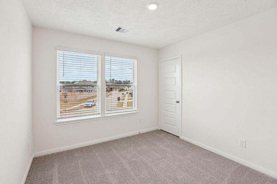 Secondary bedroom features plush carpet, neutral paint, lighting, large windows with privacy blinds, and ample sized closet space.