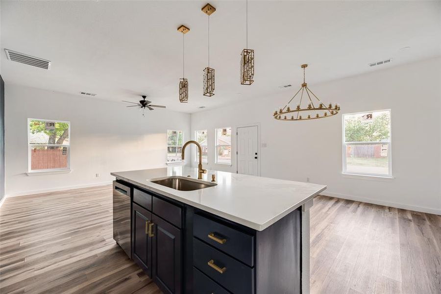 Kitchen featuring a center island with sink, a ceiling fan, open floor plan, light wood-style flooring, and dishwasher