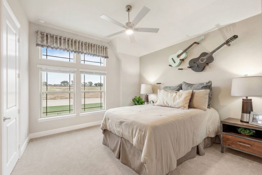 Bedroom with vaulted ceiling, ceiling fan, large windows, and two guitars mounted on the wall
