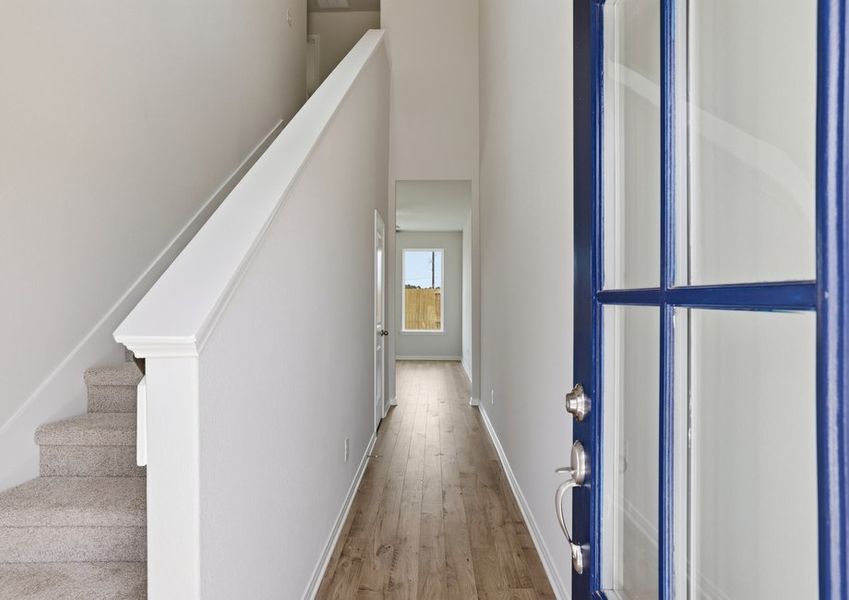 Foyer entryway featuring wood-look vinyl flooring, a staircase with white railing, and a hallway leading into the home.