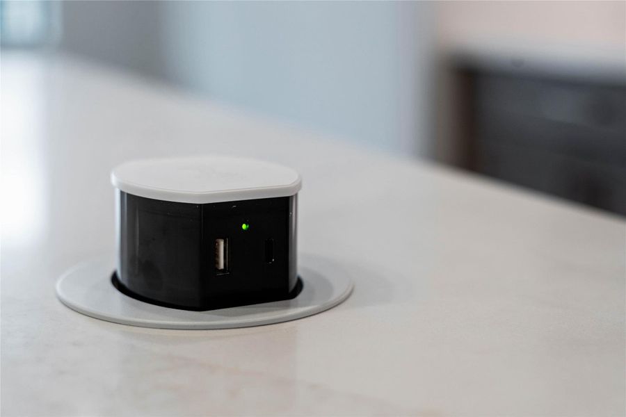 The added pop-up electrical outlet fixture sits nearly flush with the countertop when not in use, preserving a clean, uncluttered aesthetic. A simple press on the top causes the unit to rise up, providing access to power.