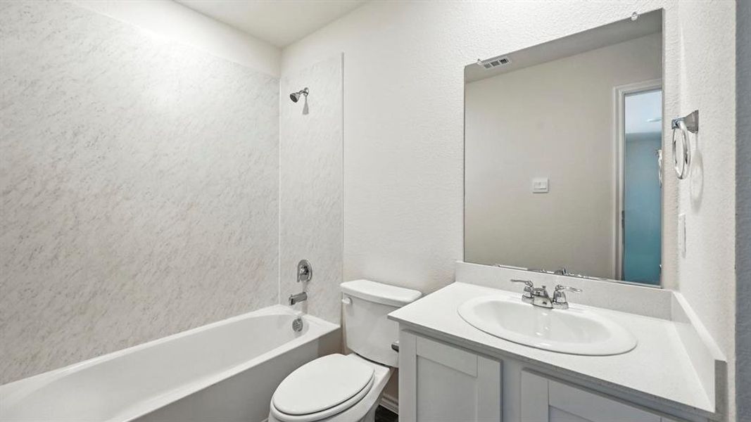 Full bathroom featuring a white tub, coordinating shower surround, and a white vanity with a single basin sink