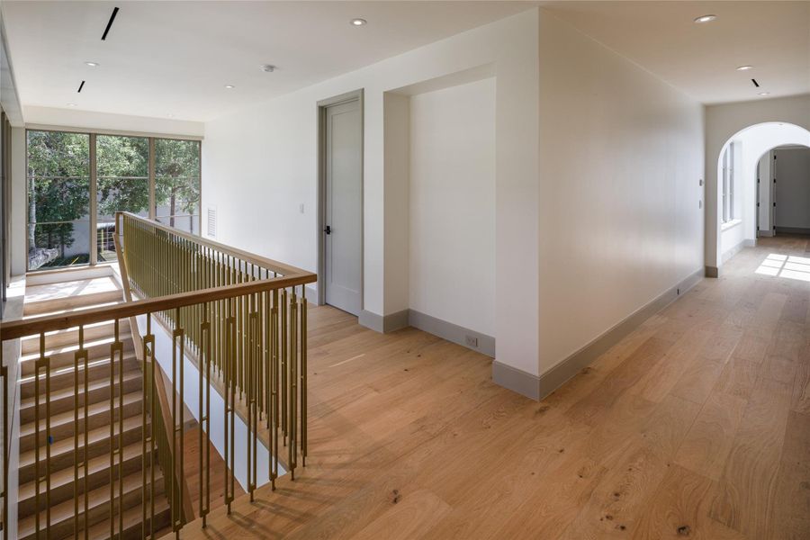 Even the hallway got the good details. White oak floors continue upstairs alongside custom brass stair rails, while arched openings and abundant natural light keep the second level feeling every bit as considered as the first.