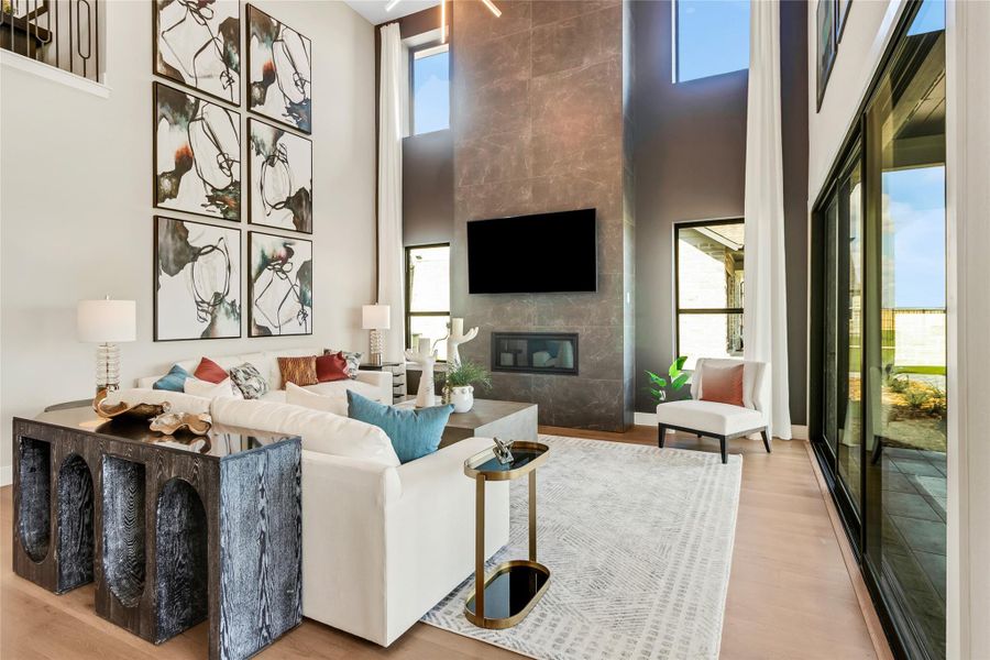 Living room with a towering ceiling, a tiled fireplace, and wood finished floors Living room with a towering ceiling, a tiled fireplace, and wood finished floors