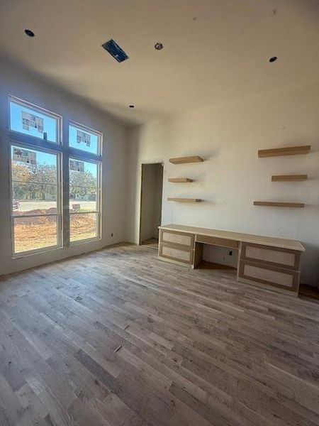 Large office space with beautiful hard wood floors, build ins, floating shelves and a separate closet for media equipment.