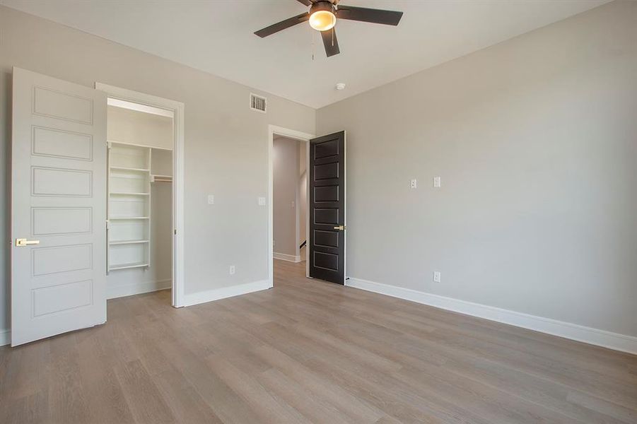 Unfurnished bedroom with ceiling fan, light hardwood / wood-style floors, a walk in closet, and a closet