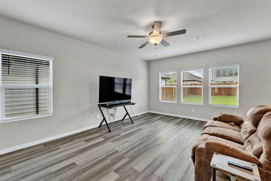 This room features wood-look flooring, light-colored walls, and a ceiling fan with a light fixture