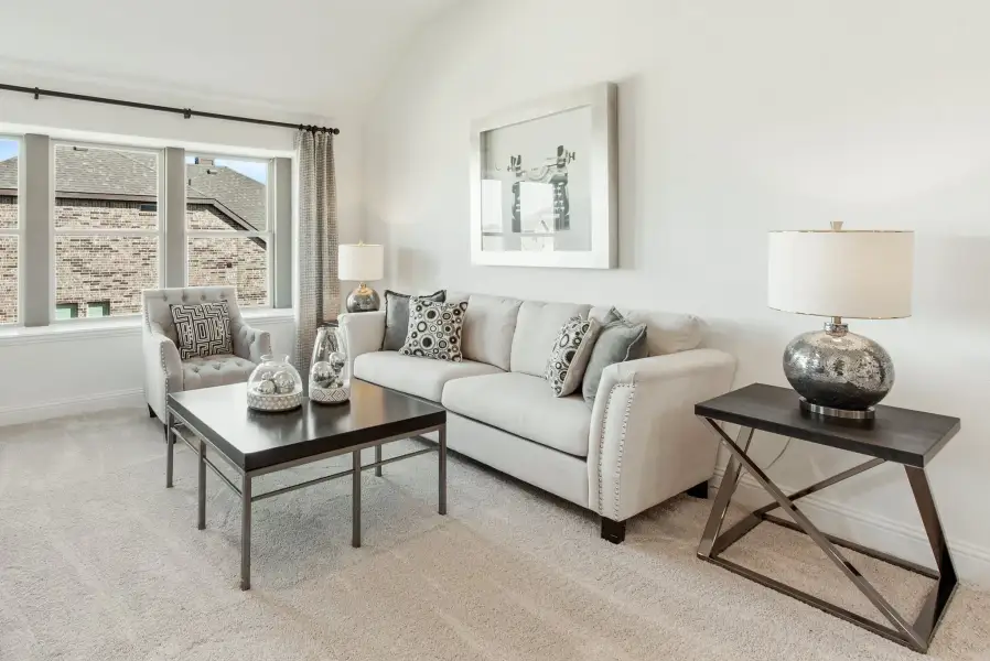 Living room with vaulted ceiling, gray sofa, accent chair, and dark coffee table on carpet