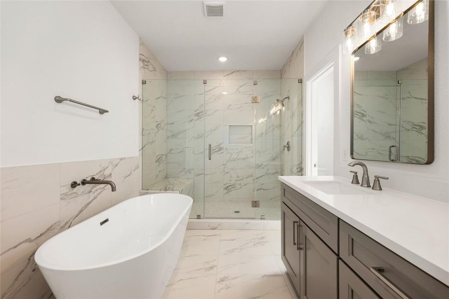 This move-in ready primary bathroom offers plenty of space to share. The stained cabinetry with light countertops and dual sinks are enhanced by modern mirrors - perfect to get ready for your day! The modern tile flooring, soaking tub and oversized walk-in shower with seat, sleek dark and modern finishes complete this gorgeous primary bathroom for a polished look.