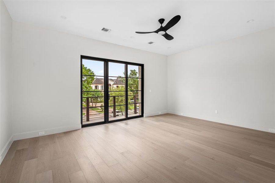 Bedroom 3 features exquisite white oak hardwood flooring, an ensuite bathroom with a walk-in closet, and an oversized glass door and windows providing direct access to the front balcony and flooding the room with natural light, while offering a seamless indoor-outdoor connection.