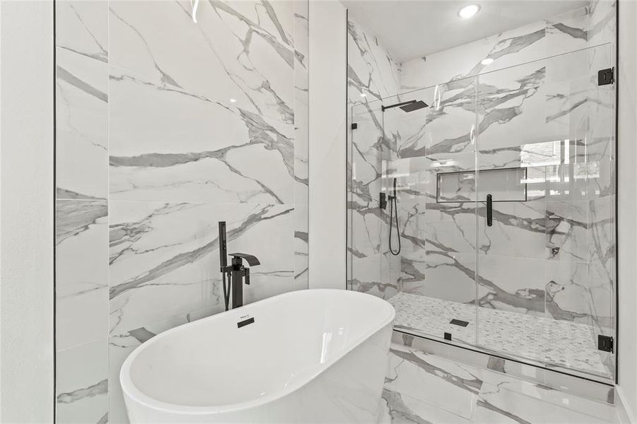 Full bath with marble tiled floors, a freestanding bath, and a marble finish shower