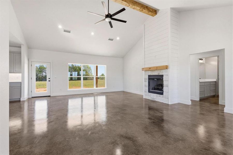 Spacious living area featuring polished concrete floors, a vaulted ceiling with a ceiling fan, and recessed lighting