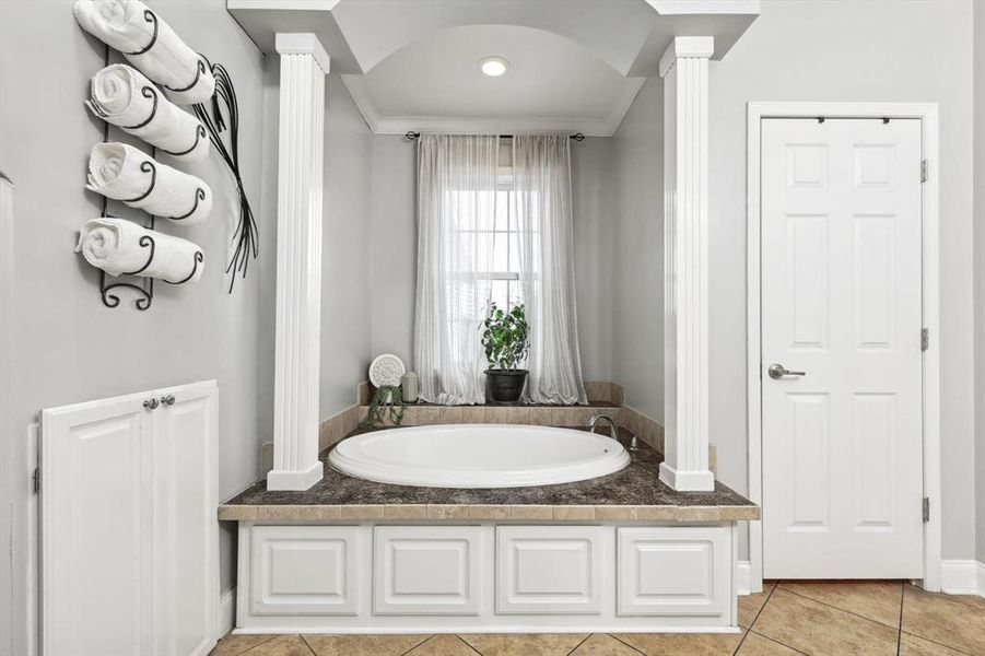 Bathroom with a washtub, tile patterned flooring, ornamental molding, and decorative columns