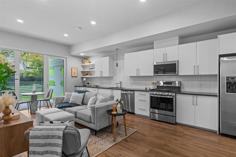 Kitchen with dark wood finished floors, dark countertops, open floor plan, stainless steel appliances, and a sink