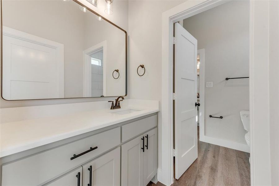 Bathroom with hardwood / wood-style floors, vanity, and toilet