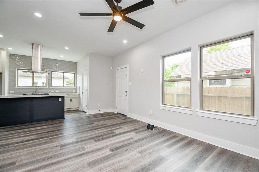 Another view of this modern family room, There are two windows providing natural light, and a contemporary ceiling fan is installed. The space appears new and ready for move-in.