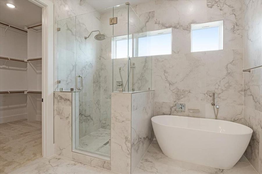 Bathroom with tile floors, tile walls, and independent shower and bath