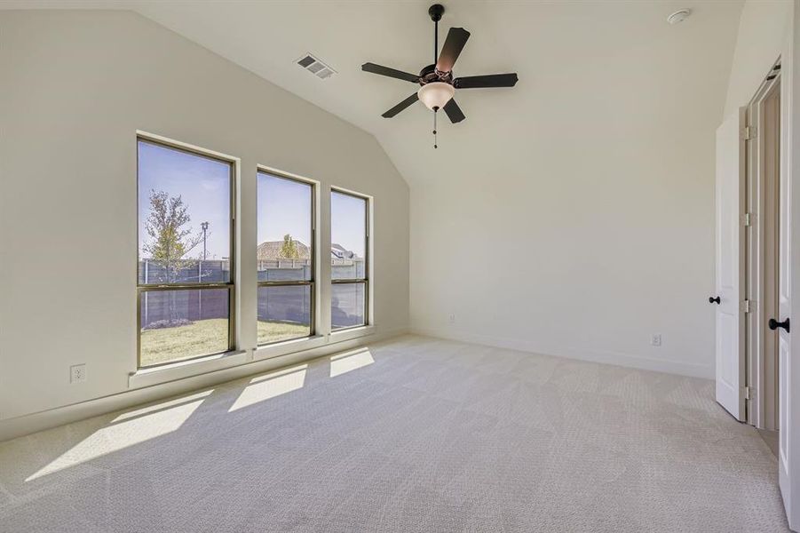 Empty room featuring light carpet, lofted ceiling, and ceiling fan Empty room featuring light carpet, lofted ceiling, and ceiling fan