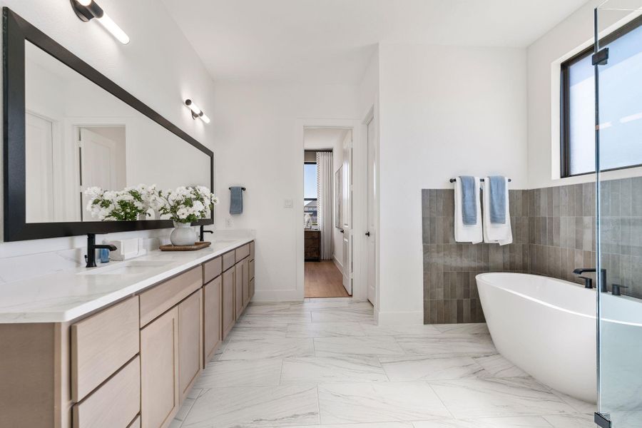 Expansive primary bathroom featuring a dual-sink vanity with quartz countertops, oversized framed mirror, and designer lighting