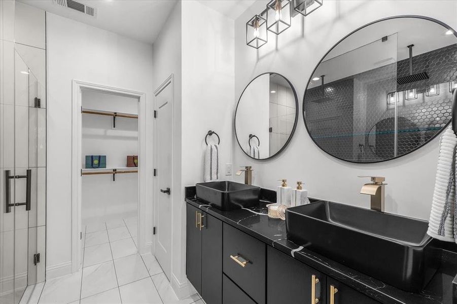 Full bath featuring a shower stall, a walk in closet, double vanity, and light tile patterned floors