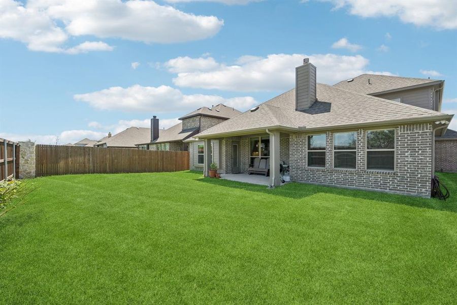 Back of house with a fenced backyard, a shingled roof, brick siding, and a patio Back of house with a fenced backyard, a shingled roof, brick siding, and a patio