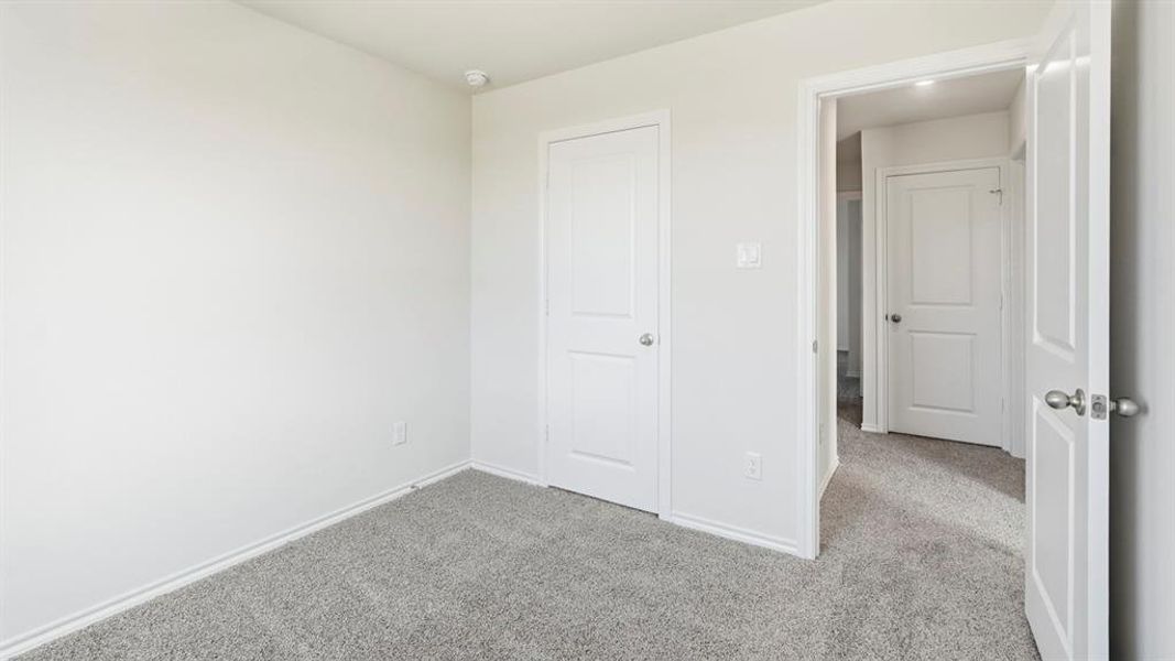Unfurnished bedroom featuring light carpet and baseboards