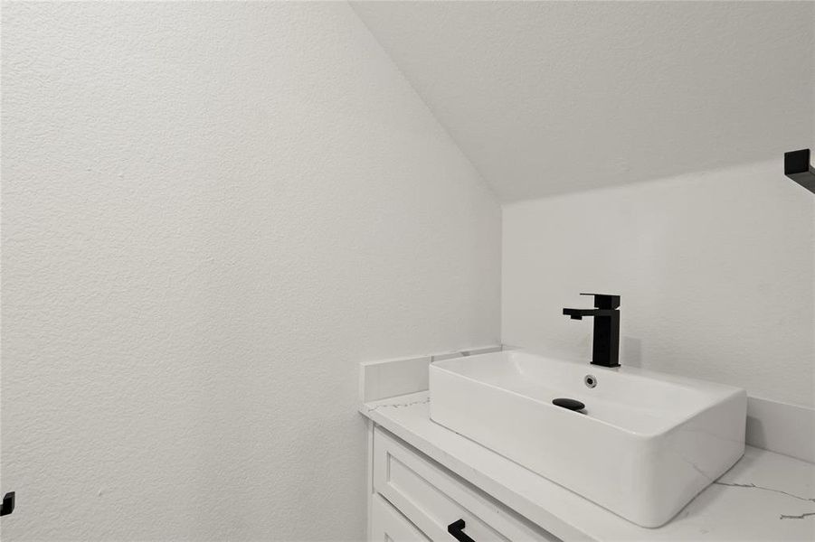 Bathroom featuring lofted ceiling and vanity