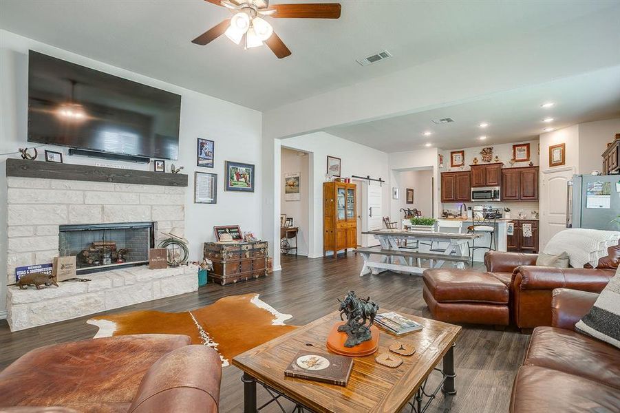 Living room with a barn door, ceiling fan, dark wood finished floors, a fireplace, and recessed lighting Living room with a barn door, ceiling fan, dark wood finished floors, a fireplace, and recessed lighting