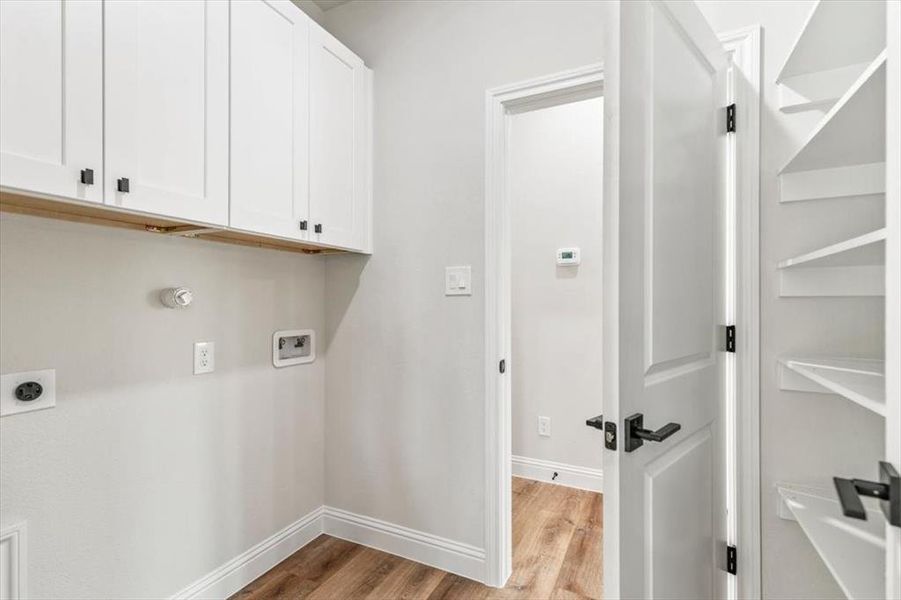 Laundry area featuring white cabinetry, a wood-finish shelf, and connections for appliances