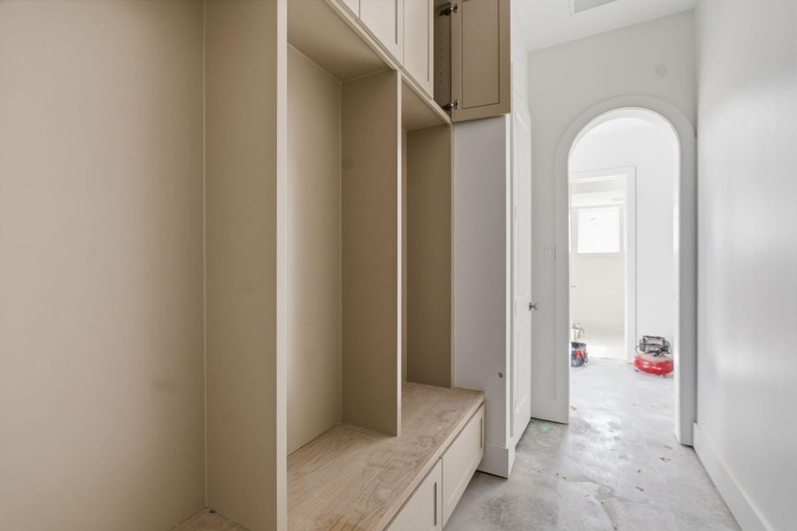 Garage entry opens into a dedicated mudroom with custom built ins for shoes, backpacks, and everyday drop zones. The arched doorway creates a clean, intentional transition into the main living spaces.