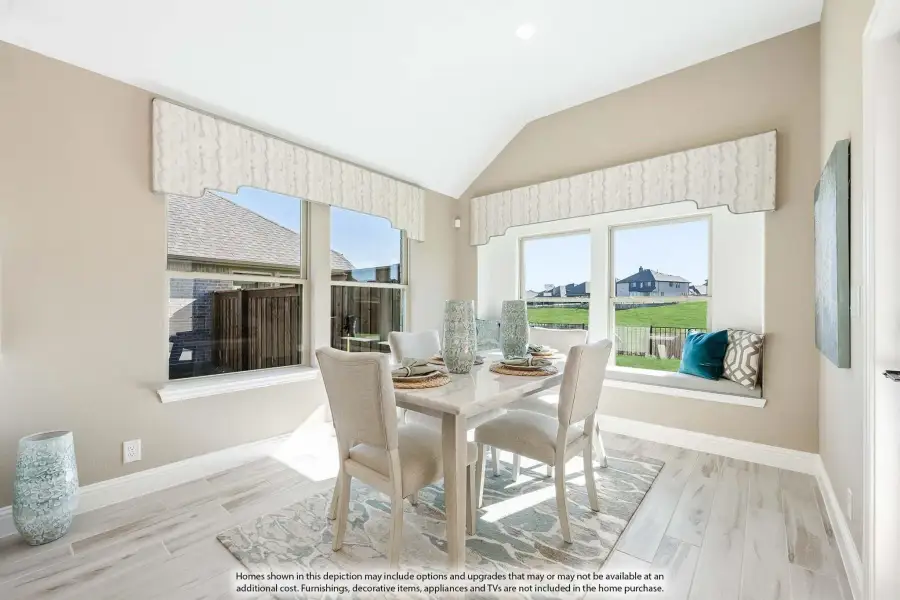 Bright dining area with vaulted ceiling, four-chair table, window seat, and light wood floors