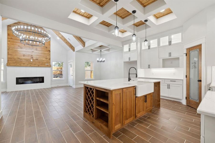 Kitchen with sink, white cabinetry, hanging light fixtures, a kitchen island with sink, and beamed ceiling