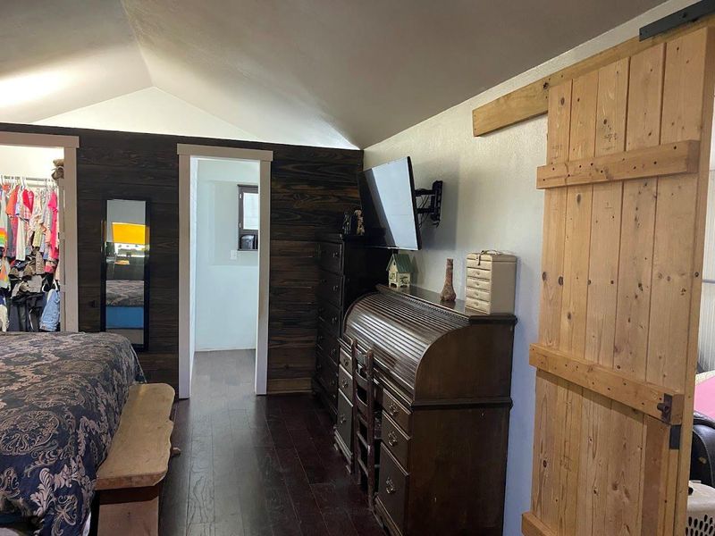 Bedroom with dark wood-type flooring, lofted ceiling, and a spacious closet