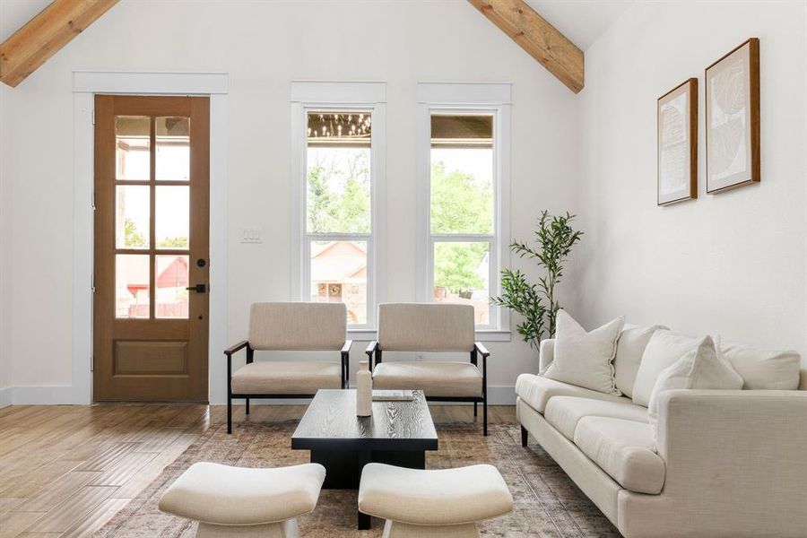 Living room with vaulted ceiling with beams, hardwood / wood-style floors, and plenty of natural light