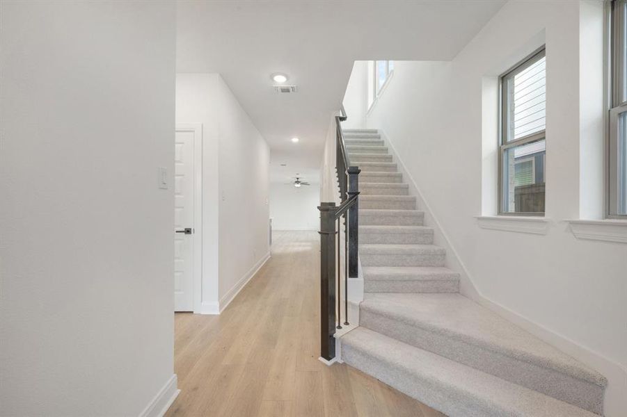 Carpeted staircase with black wood newel posts and metal balusters