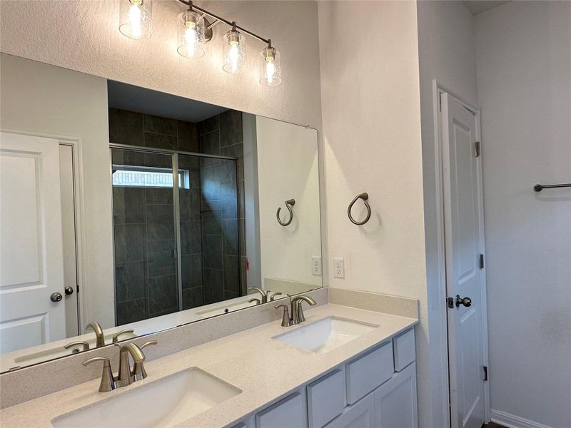 Bathroom featuring a shower stall and double vanity